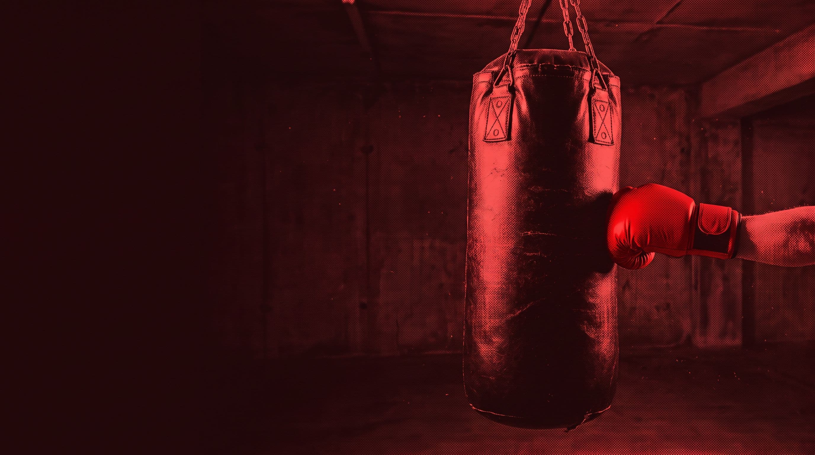 Sac de frappe lourd suspendu dans un garage, gant rouge en pleine frappe
